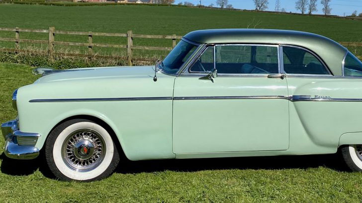 Left side view of a pale groom American Packard Super Clipper  with spokes chrome wheels and white wall tires