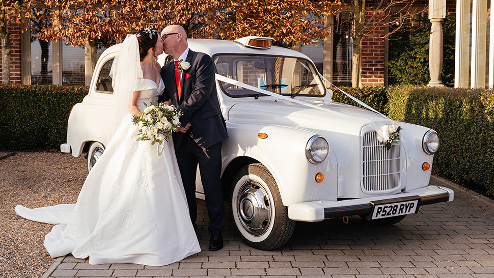 Bride and Groom kissing in front of a classic white Taxi Cab