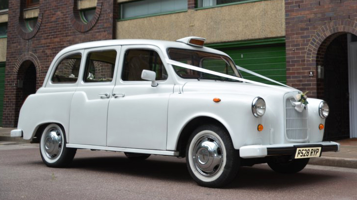 white Classic taxi cab with white wall tires decorated with white wedidng ribbons