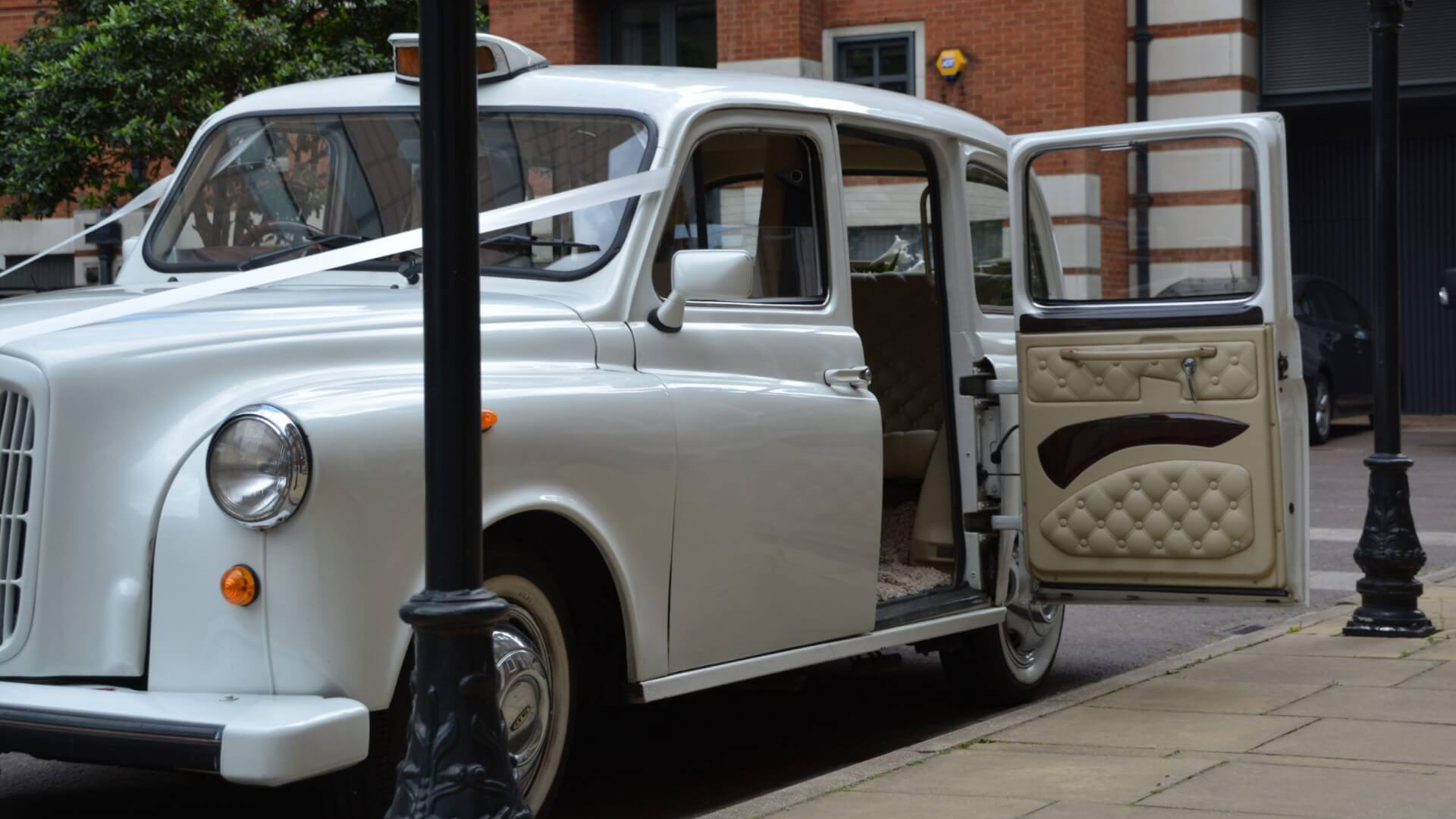 White taxi Cab parked in the street of London with rear passenger door open