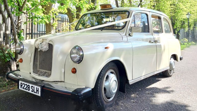 Classic Ivory Classic Taxi Cab decoratedwith ribbons and wedding flowers on the front grill