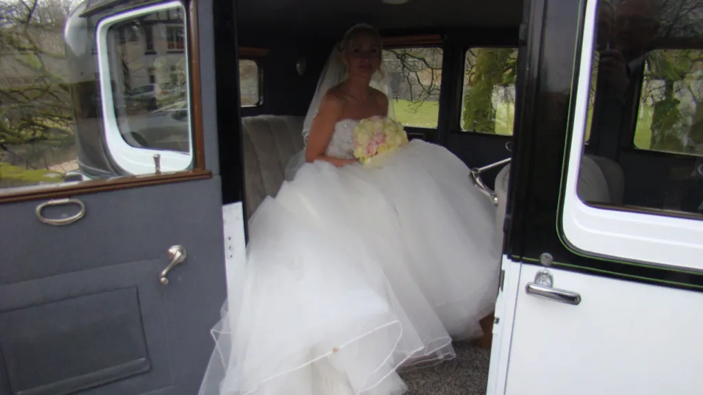 Bride with large white wedding dress seating inside the vintage Franklin.