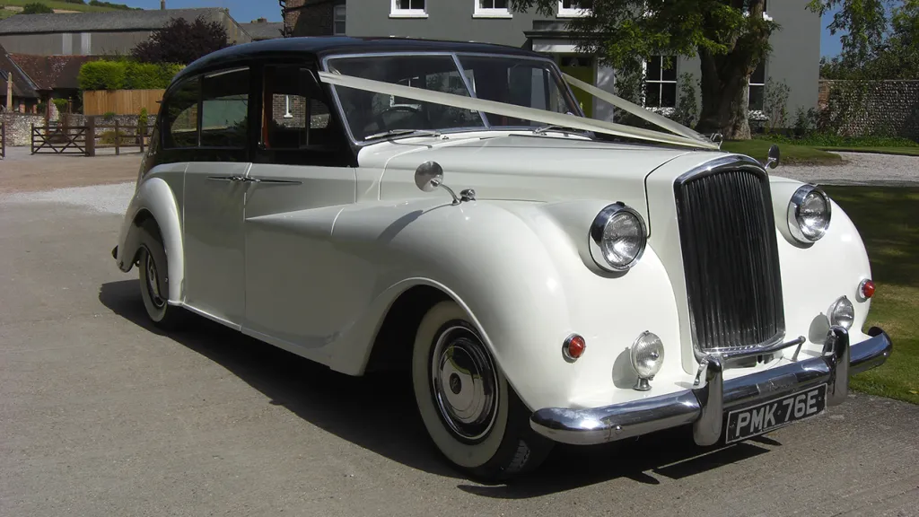 Side view of a White Austin Princess Limousine decorated with ivory Ribbons, white wall tires and black roof