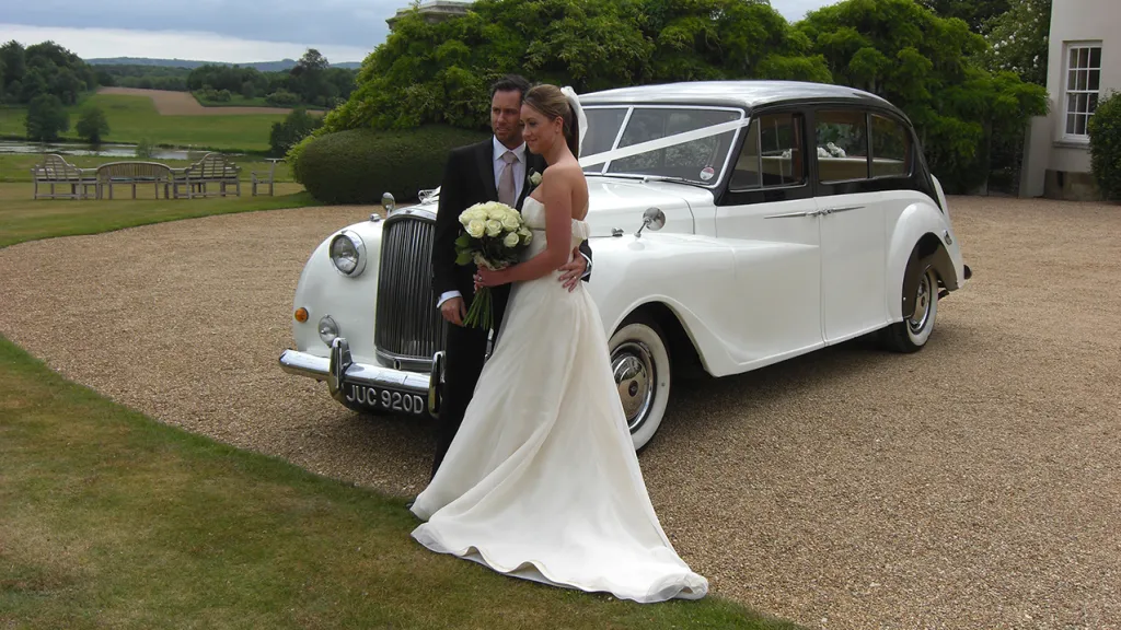 Bride and Groom standing in front of an Austin Princess Limousine