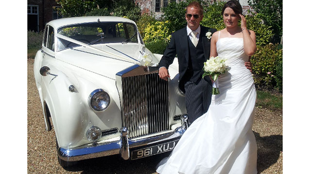 Bride and Groom standing in front of Classic rolls-royuce silver cloud in fron of their wedding venue
