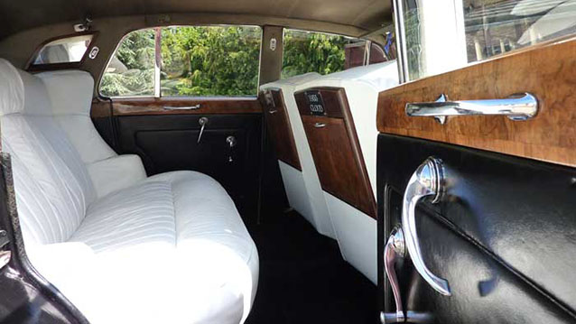 Interior rear seating showing creaml leather interior, wooden picnic table and wooden door cards
