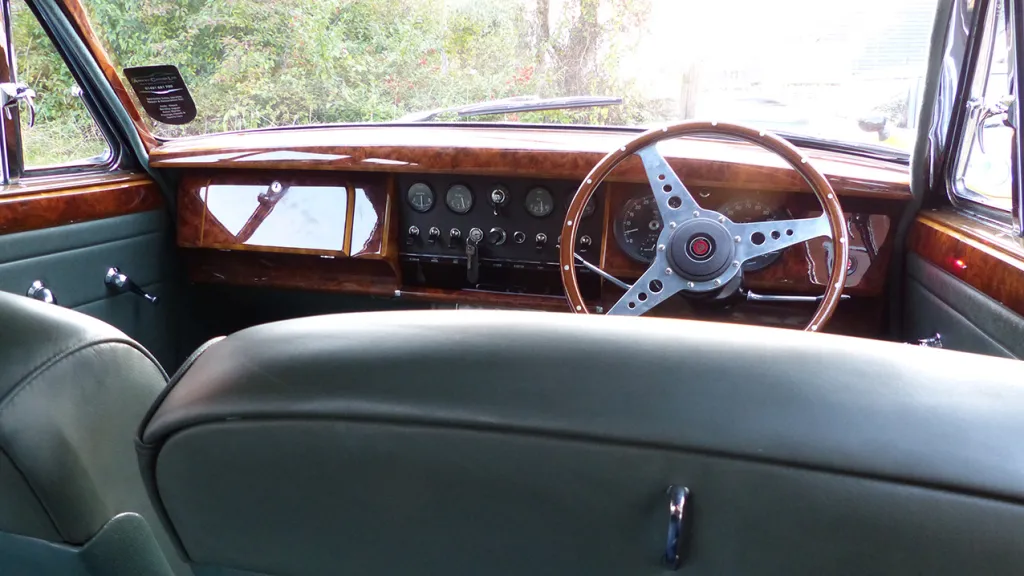 interior photo taken from the rear seat towards the front to show the wooden dashboard and steering wheel.
