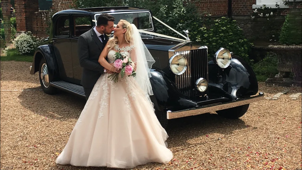 Bride and Grom kissing in front of vintage Rolls-Royce Phantom II Continental LWB