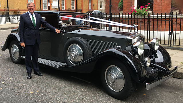 Rolls-Royce Phantom II Continental LWB with chauffeur standing in front of the vehicle holding the door