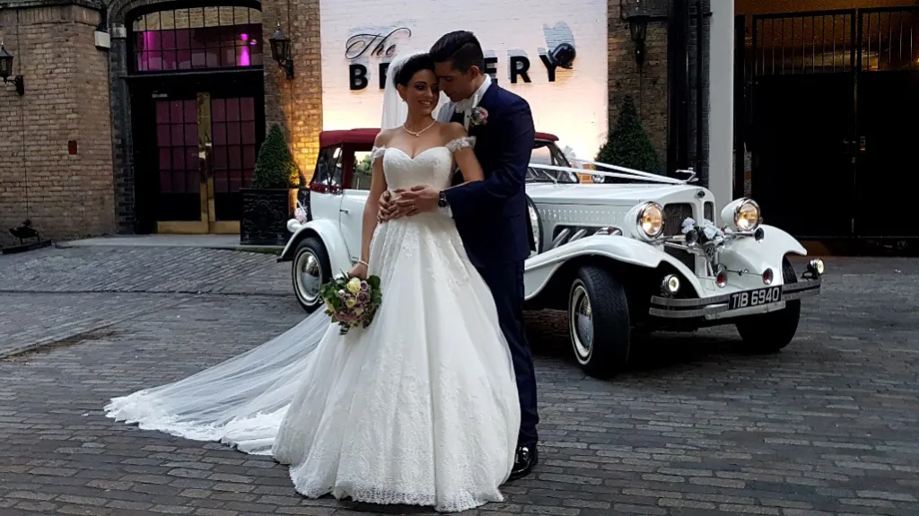 Bride and Groom posing for photos next to a Beauford dressed with ribbon decoration in front of "The Brewery" Venue in London