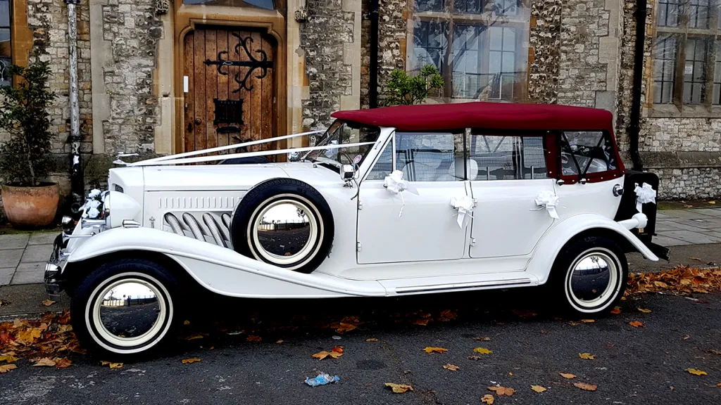 Left Side of Beauford with white ribbons accross its bonnet and burgundy soft top roof is closed