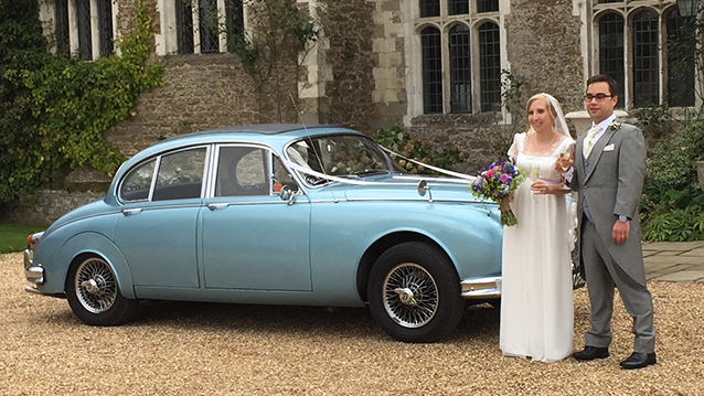 Bride and Groom standing in frotn of a classic Daimler 250 V8
