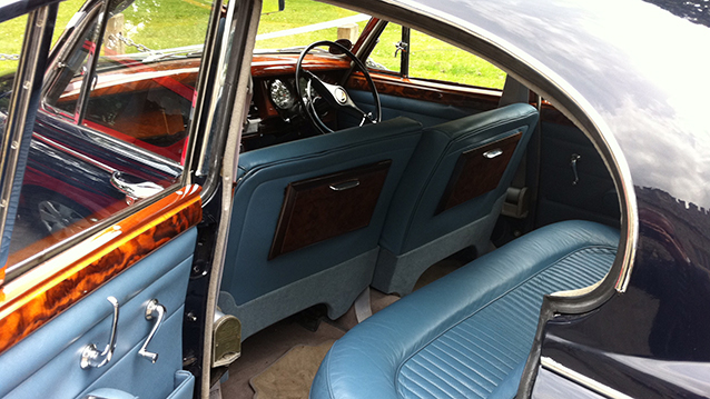 Rear interior view of classic Daimler 250 V8 light blue interior, wooden door tops and picnic tables