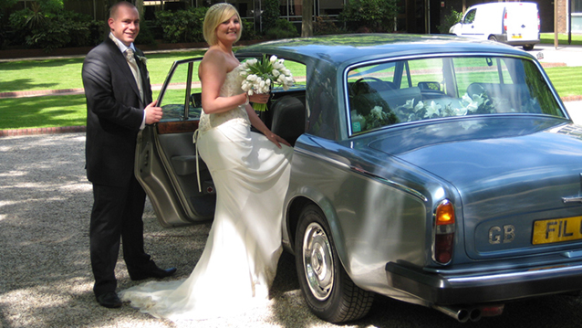 Groom holding the door while the Bride is entering the rear of the Rolls-Royce Silver Shadow II