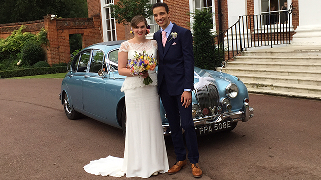 Bride and Groom posing for photos in front of Blue Daimler 250 V8