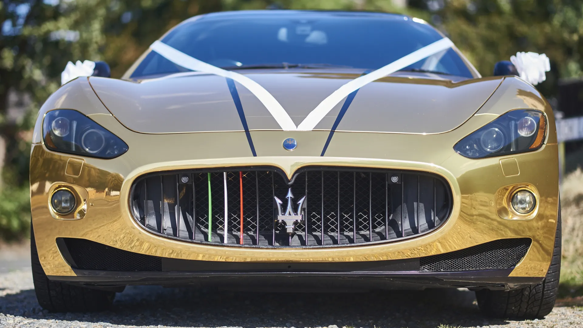 Full Front view of Maserati GranTurismo decorated with White ribbons and Trident logo in the middle of the grill