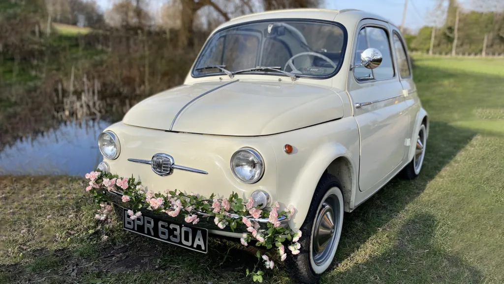 How can I thank Amy enough?! I&#8217;m not sure if I can express my gratitude in one review but I&#8217;ll certainly try. I got married last Saturday in Surrey and my wedding was a dream come true. I&#8217;ve also got a fiat 500 myself so this was a nice sentimental touch to the day and I can say that choosing lily (the cream fiat 500) was one of the best decisions I made for the big day. The service was impeccable, Amy our kind driver was so polite, timely and professional. She picked us up in immaculate Lily, all prepped with pink roses at the front and a &#8216;just married&#8217; basket at the back! (I even got a choice on the flowers)
Amy picked us up in Lily ahead of time, and she had even prompted us gently that we may need to make a move on incase of traffic and boy, I&#8217;m so glad she did because otherwise we would have been late to the registry office!
Once we got there, Amy waited outside for the whole ceremony to finish INCLUDING photos which took a while but Amy was so patient with us. I cannot thank her enough for the service. She was fabulous&#8230; the car was in excellent condition, without a speck of dirt on her. Everyone complimented and waved at us because it was such a beautiful car and notably, a bridal one too !
She was gentle and so professional and as a bride who was rather nervous on the day, she made the whole journey so much easier and less tense. These cars are beautiful and I can assure you, better than any other you&#8217;ll find in the market as they&#8217;re truly one of a kind in this day and age. On behalf of my husband and I, thank you. Thank you so much. Suji &amp; Jong.
