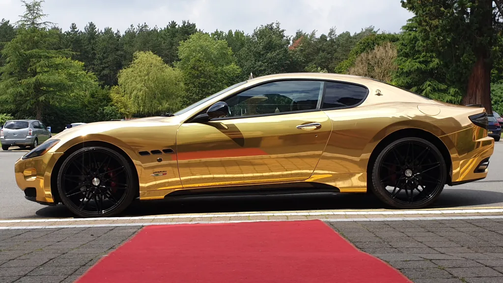 Left side view of Gold Maserati GranTurismo with Red Carpet leading to the vehicle