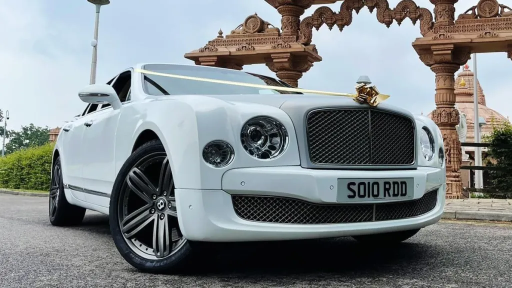 Modern White Bentley Mulsanne in front of an Asian temple decorated with gold ribbons
