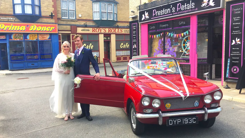 Red Classic Triumph with white ribbons on Coronation Street set for the wedding of Daniel and Sinead.