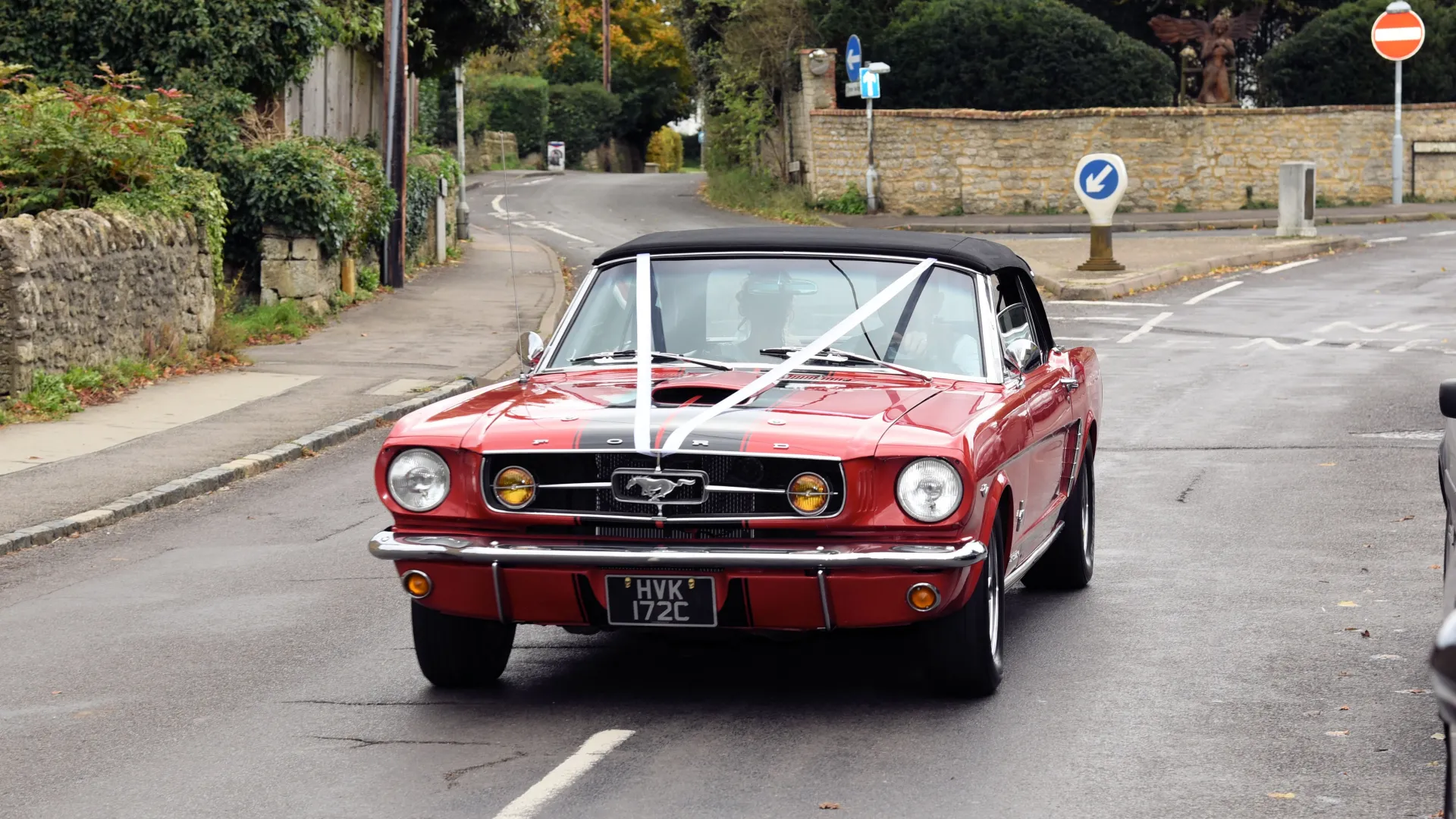 Ford Mustang Convertible decorated with white ribbons and soft-top black roof close.