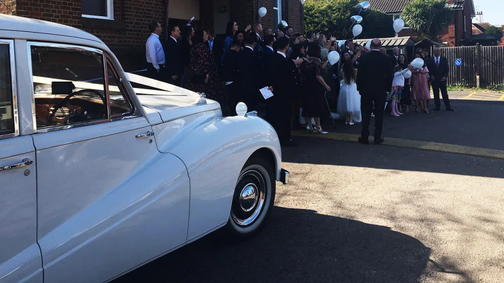 photo of the car with wedding guest in front of the wedding venue in background