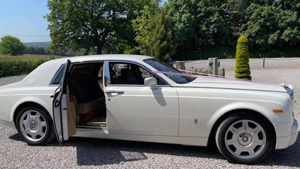 Side view of White rolls-Royce Phantom with door open showing cream leather interior