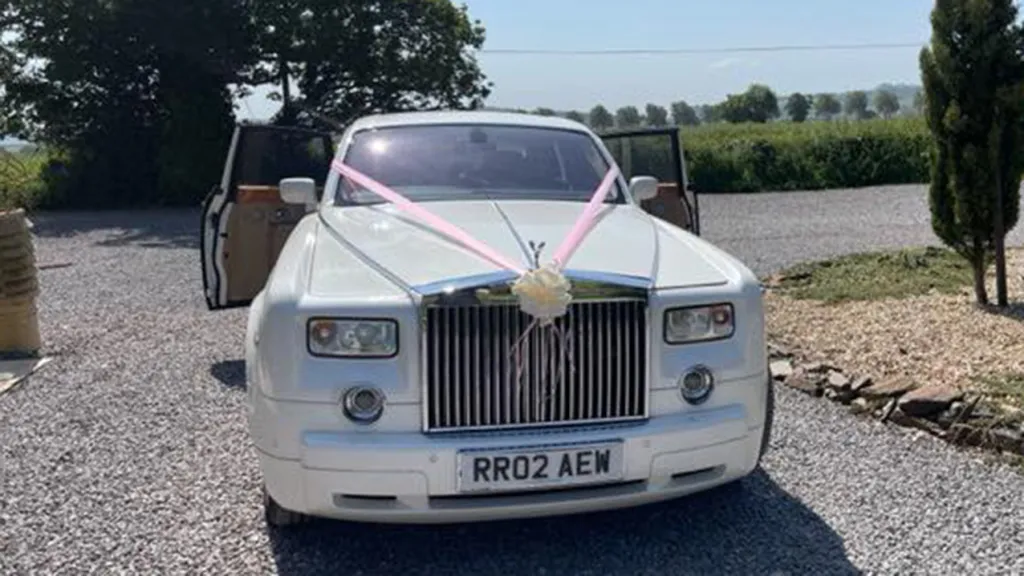 Front view of Rolls-Royce Phantom in white decorated with white ribbons and rear door open